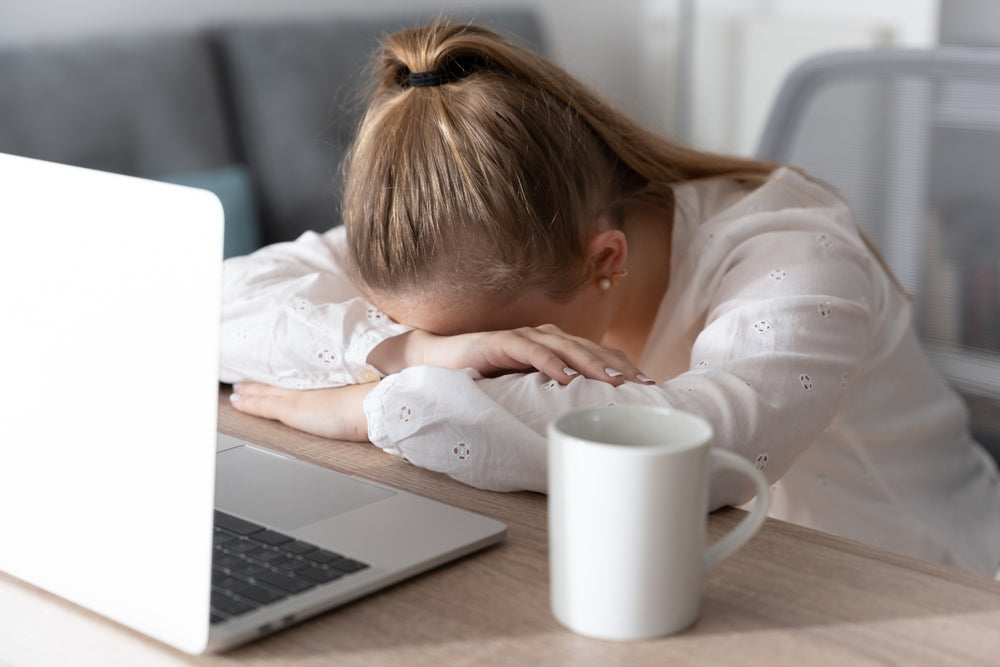 überarbeitete Frau vor dem Laptop mit Kopf auf dem Tisch